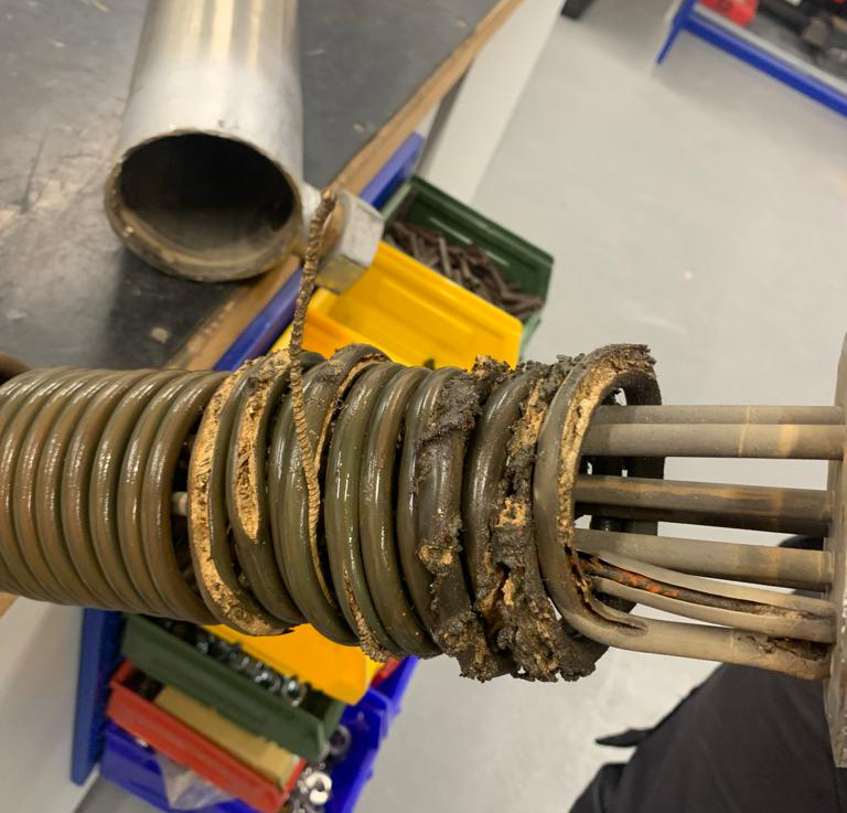 L'immagine mostra il dettaglio di un riscaldatore elettrico scoppiato, durante intervento di manutenzione su un termoregolatore 